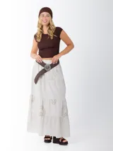 Falda larga de estilo campesino color crudo, confeccionada en algodón italiano con apliques florales al tono. Tiene cintura elastizada y cinto de rafia elastizado desmontable.