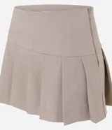 Short pollera de tiro alto en color beige, con diseño de sastrería, tablas delanteras y ruedo asimétrico.