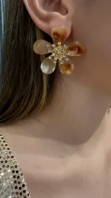 Aros con diseño de flor en tonos carey, con centro dorado decorado con cristales brillantes.