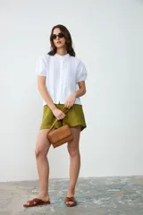 Cartera de hombro pequeña de cuero tostado, con solapa frontal decorada con bordados artesanales en los bordes y cierre de broche magnético. Incluye asa corta de mano y forro interior.