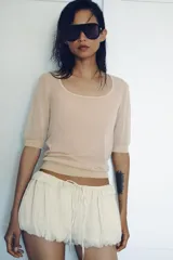 Shorts de tiro bajo con diseño abullonado, confeccionado en tejido ligero con sutiles rayas verticales. Presenta cintura elástica ajustable con cordón y detalle de volantes en la parte superior.