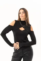 Polera negra de manga larga con diseño de hombros descubiertos y cuello alto. Presenta un recorte frontal en el pecho que crea un efecto de superposición.