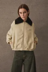 Campera bomber de paño color azul marino, con cuello de piel sintética en color marrón desmontable, cierre frontal y puños elásticos. Presenta logo bordado en el frente y bolsillos laterales.