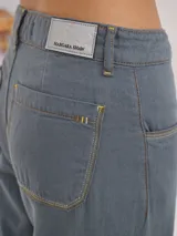 Pantalón de tiro medio alto, color beige, con bolsillos delanteros y traseros. Presenta detalles de atraques y triples costuras en color amarillo. Confeccionado en una mezcla de lino, algodón y viscosa.