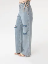 Pantalón de jean celeste de corte ancho, con roturas en las rodillas y apliques de strass.