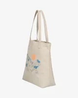 Tote bag Billabong de lona color beige con diseño estampado de la colaboración con Ty Williams que muestra figuras cargando una tabla de surf y un sol rosado.