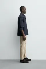 Pantalón chino de corte ajustado, color beige, con bolsillos laterales y bolsillos traseros de vivo. Cuenta con cierre frontal de cremallera y botón.