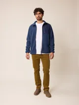 Campera de polar color beige con cierre frontal completo y cuello alto. Presenta un bolsillo en el pecho con cierre y detalle de parche con logo. El diseño combina paneles de tejido polar con detalles en tejido técnico en la zona del pecho.