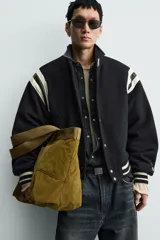 Bolso tipo shopper de gran capacidad, confeccionado en tejido con textura de pana. Cuenta con dos asas de mano resistentes, un bolsillo frontal plano y cierre principal mediante botón a presión. El interior incluye un bolsillo con cierre de cremallera.