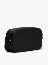 Cartera tipo bandolera de diseño compacto y minimalista, confeccionada en poliuretano con acabado liso. Presenta cierre de cremallera superior y una insignia metálica distintiva de Tommy Jeans en el centro del frente.
