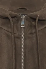 Chaqueta bomber de efecto ante en color marrón, con capucha ajustable mediante cordones, cierre frontal con cremallera, bolsillos laterales y bajo con elástico interior.