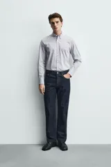Camisa de corte regular fit confeccionada en tejido de algodón con estampado de microcuadros. Presenta cuello abotonado, manga larga con puños abotonados y cierre frontal de botones.