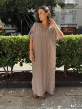 Vestido largo de tejido a rayas verticales marrones y blancas, con escote en V y mangas cortas.