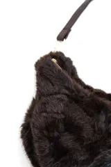 Cartera bandolera de diseño semicircular con textura de pelo sintético y estampado animal print. Cuenta con cierre superior y correa ajustable y desmontable de cuero sintético marrón con herrajes metálicos dorados.