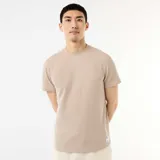 Camiseta de cuello redondo y manga corta color beige, con textura de nido de abeja y pequeña etiqueta decorativa en el borde inferior.