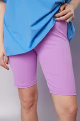 Calza corta tipo biker de color lila, ajustada al cuerpo, confeccionada en tejido elástico.