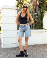 Bota de caña alta confeccionada en cuero negro, con suela track de goma. Presenta un diseño versátil con dos hebillas ajustables en la parte superior de la caña y una correa decorativa con tachas metálicas y argollas en la zona del tobillo.