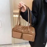 Cartera de cuero sintético color marrón, de diseño rectangular con doble asa superior para hombro, cierre principal con cremallera y dos bolsillos frontales externos con solapa.