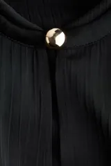 Vestido túnica negro de manga larga con cuello redondo ribeteado y abertura frontal con botón metálico. Presenta un tejido con textura arrugada y puños amplios con botón.