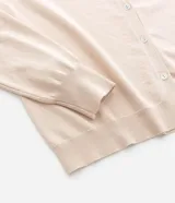 Cardigan de punto color beige, con cuello redondo, cierre frontal abotonado y puños y ruedo acanalados.