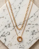Collar doble de acero dorado compuesto por una cadena de eslabones alargados y una cadena de bolitas con un dije central de dos círculos entrelazados.