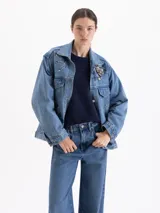 Chaqueta de denim de corte oversize con diseño de bordados y estampas exclusivas. Posee cuello clásico, cierre frontal con botones metálicos y bolsillos con solapa en el pecho.
