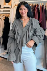 Camisa de pana fina color azul, con diseño de volados en los hombros y mangas largas abullonadas con puños elásticos. Presenta cierre frontal con botones y cuello con detalle de volado.