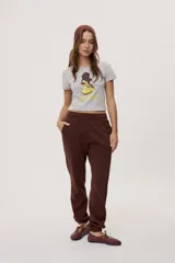 Remera blanca de manga corta, con estampa frontal de un pato de hule con turbante y labios pintados, acompañada de la frase "In all else fails, denial".