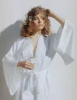Kimono largo de seda blanca con mangas amplias y cinturón ajustable del mismo género.