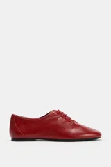 Zapato plano de piel color rojo, con cierre de cordones al tono, puntera redonda y suela baja.