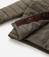 Campera puffer negra con cuello alto, cierre frontal con botones a presión, bolsillos laterales y un bolsillo cargo en el pecho. Presenta un diseño acolchado y forro interior suave.