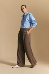 Pantalón ancho color marrón, de silueta moderna y calce cómodo, con diseño limpio y fluido. Presenta cierre frontal con botón y cordones ajustables en la cintura.