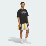 Remera negra de algodón con ajuste holgado, cuello redondo y mangas cortas. Presenta un estampado gráfico frontal con la palabra "ADIDAS" en estilo universitario con borde amarillo y azul, acompañado de un emblema circular en el centro.