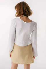 Top de lino italiano color blanco, con escote en V, mangas largas estilo globo y detalle de jareta frontal ajustable con volado en el ruedo.