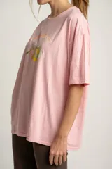 Remera rosa de algodón con calce oversize y estampa de limones y naranjas con la frase "Paris Orange".