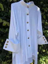 Camisola blanca de corte holgado con cuello alto y mangas largas con puños anchos abotonados.