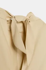 Vestido midi de gabardina en color beige, con cuello subido, manga corta y falda acampanada con caída fluida.