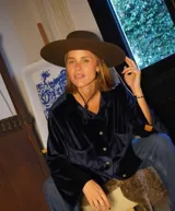 Camisa azul marino de terciopelo con cuello clásico, cierre frontal con botones dorados, mangas largas con puños abotonados y dos bolsillos de parche en el pecho.