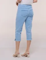 Capri blanco de corte ajustado, con tiro alto y pretina ancha elastizada tipo faja. Presenta bolsillos falsos al frente con remaches, piernas entalladas con pequeñas aberturas en los laterales y ruedo desflecado.