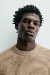 Sweater de punto color beige, de corte relajado, con cuello redondo y diseño texturizado en estructura waffle.