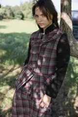 Chaqueta entallada con cuello mao y volado frontal, confeccionada en tejido tartán en tonos tierra con mangas largas en contraste color marrón oscuro. Presenta cierre frontal con botones y bolsillos delanteros.