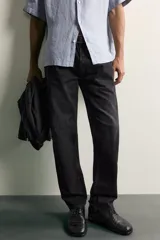 Jeans regular fit de mezclilla negra con efecto lavado, corte recto y tiro medio. Cuenta con diseño de cinco bolsillos y cierre frontal con cremallera y botón.