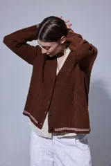 Saco tejido en lana, con diseño de rombos y trenzas en el frente. Presenta detalles de doble raya en contratono en los puños y el ruedo, cierre frontal con botones y pin bordado en la manga.