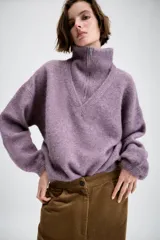Jersey de punto con cuello alto y cierre frontal de cremallera metálica, de manga larga con puños ajustados y diseño holgado.