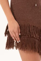 Vestido corto sin mangas de punto color marrón con sutil brillo, corte recto y dobladillo asimétrico adornado con flecos largos.