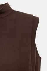 Top de punto blanco sin mangas con cuello subido, hombreras marcadas y espalda descubierta con cierre de botones.