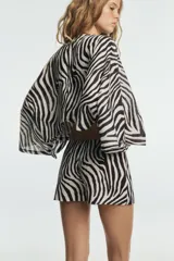 Kimono de lino con estampado animal print de cebra, escote en pico y mangas largas amplias. Presenta un diseño corto con bajo asimétrico.