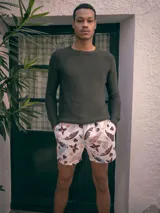 Short de baño blanco con estampado de hojas de palmera, piñas y flores en tonos marrones, rosados, celestes y naranjas.