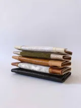 Billetera de cuero negro con diseño de solapa en forma de V y textura combinada de cuero liso y efecto croco. Cuenta con cierre mediante broche a presión.