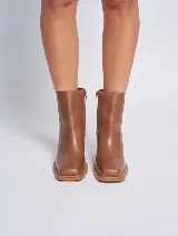 Bota de cuero color marrón con caña baja, punta cuadrada y taco geométrico de madera.